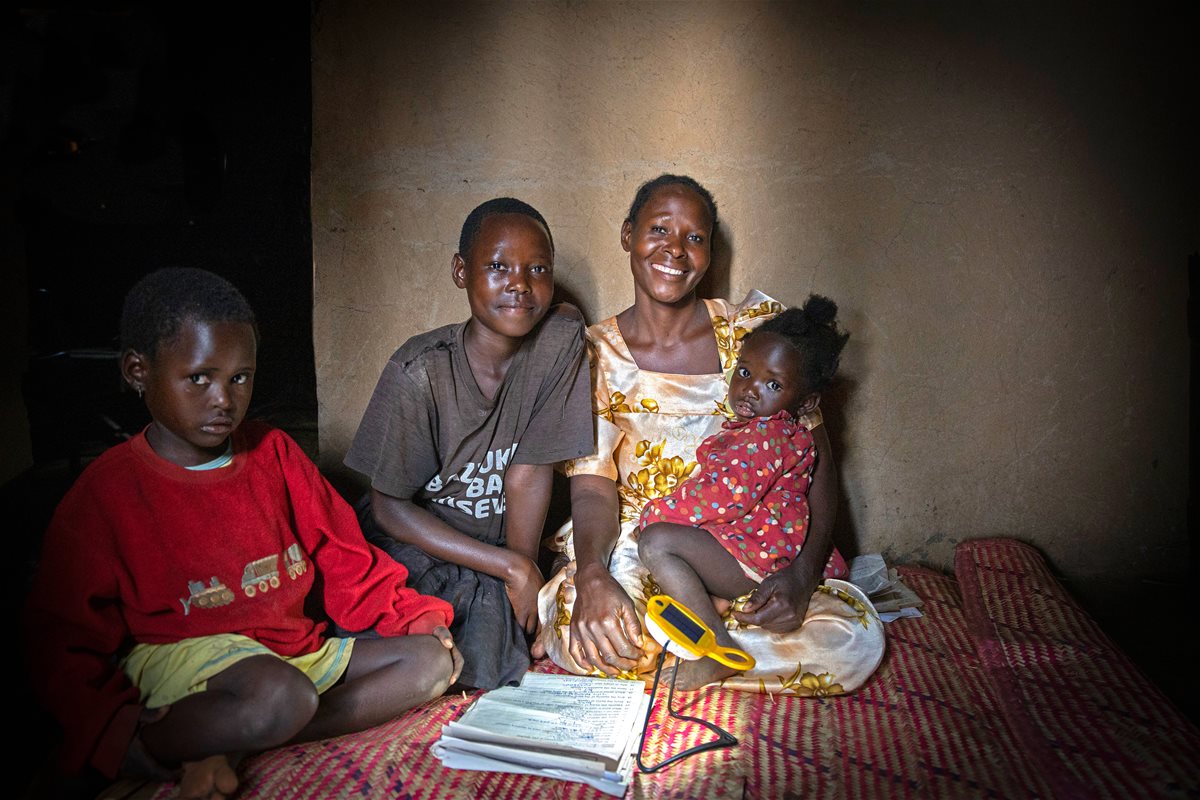 Familien til Sara Nayigaga fra Uganda sitter i lyset fra solcellelampa